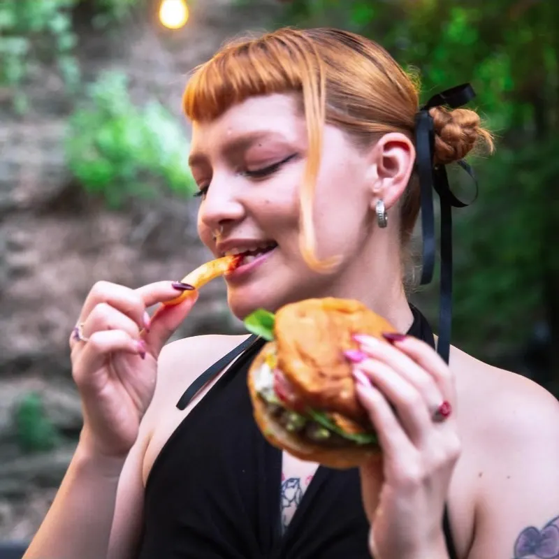 Persona comiendo una hamburguesa en el patio